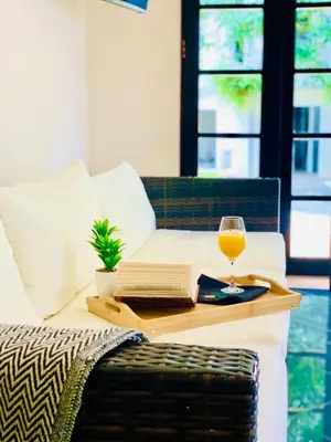 a table with a glass of wine and a book at Hotel Mango Airport in Alajuela City