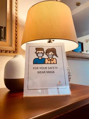 a sign sitting on a table next to a lamp at Hotel Mango Airport in Alajuela City