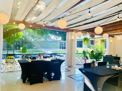 a restaurant with black tables and chairs and a large window at Hotel Mango Airport in Alajuela City