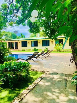 a house with a swimming pool in the yard at Hotel Mango Airport in Alajuela City