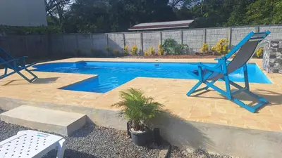 a swimming pool with two blue chairs and a palm tree at Casa en Playa Tambor - A 5 minutos de la playa in Tambor