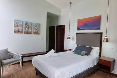 a bedroom with a large bed and a chair at Villas Töcu-Casa Perezoso in Fortuna