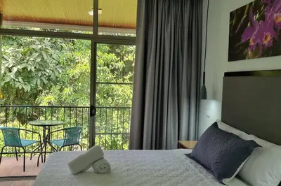 a bedroom with a bed and a balcony with a table at Villas Töcu-Casa Perezoso in Fortuna
