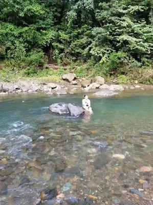 a person sitting on a rock in a river at Luxury Villa Carao - Serene Amazing Views at Finca Chilanga in San Mateo
