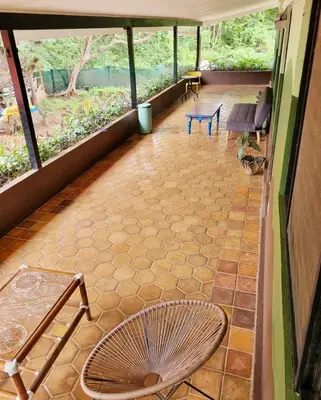 a screened in porch with a table and chairs at Casa Pura Vida Surf Hostel - Tamarindo Costa Rica in Tamarindo