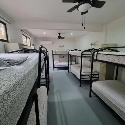 a room with three bunk beds and a ceiling fan at Casa Pura Vida Surf Hostel - Tamarindo Costa Rica in Tamarindo
