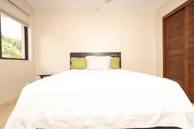 a bedroom with a large white bed and a window at Condo Pacifico in Quepos