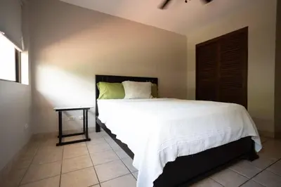 a bedroom with a large white bed and a table at Condo Pacifico in Quepos