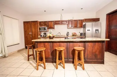 a kitchen with wooden cabinets and a island with stools at Condo Pacifico in Quepos