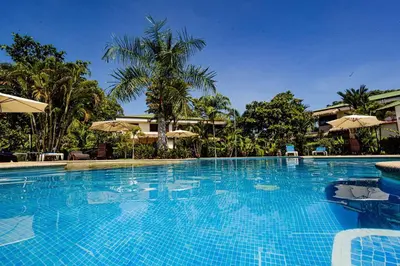 a large blue swimming pool with trees and umbrellas at Condo Pacifico in Quepos