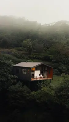 a house on a hill with two people sitting on a porch at Casas Jaguar in Monteverde Costa Rica
