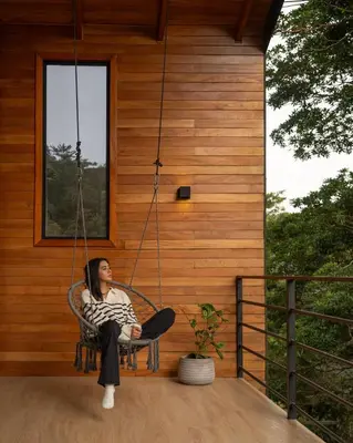 a woman sitting in a swing on the porch of a house at Casas Jaguar in Monteverde Costa Rica