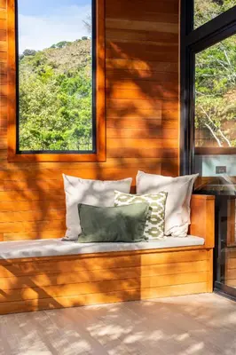 a bench with pillows on a wooden wall with a window at Casas Jaguar in Monteverde Costa Rica