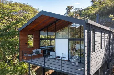 a small house with a large deck and glass windows at Casas Jaguar in Monteverde Costa Rica