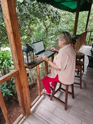 a woman sitting at a table with a laptop at Cabañas Los Jobos in Villarreal