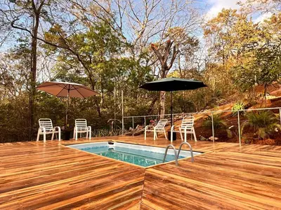 a pool with chairs and umbrellas on a deck at Cabañas Los Jobos in Villarreal