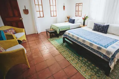 a bedroom with two beds and a couch and a chair at Encantada Ocean Cottages in Esterillos Este