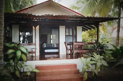 a small house with a porch with a table and chairs at Encantada Ocean Cottages in Esterillos Este