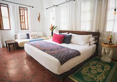 a bedroom with a large bed and a couch at Encantada Ocean Cottages in Esterillos Este