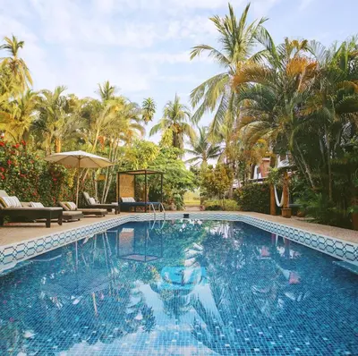 a large swimming pool with palm trees in the background at Encantada Ocean Cottages in Esterillos Este