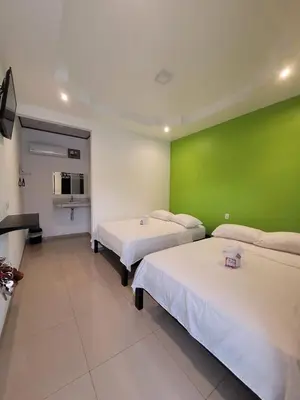 a room with two beds and a green wall at HOTEL Y RESTAURANTE RANCHO DE SEBAS in Nicoya