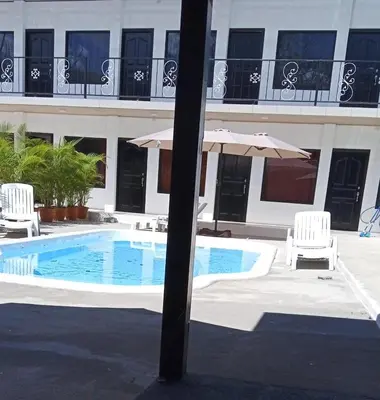 a swimming pool with two chairs and an umbrella at HOTEL Y RESTAURANTE RANCHO DE SEBAS in Nicoya