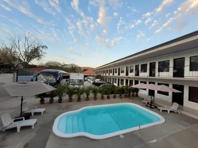 a hotel with a swimming pool in front of a building at HOTEL Y RESTAURANTE RANCHO DE SEBAS in Nicoya