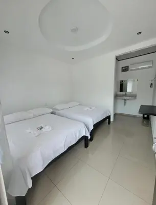 a bedroom with two beds with white sheets at HOTEL Y RESTAURANTE RANCHO DE SEBAS in Nicoya