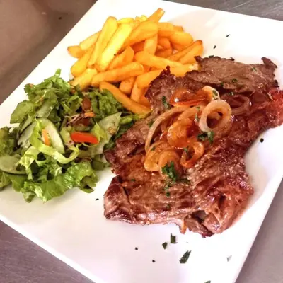 a white plate with steak and a salad and fries at HOTEL Y RESTAURANTE RANCHO DE SEBAS in Nicoya