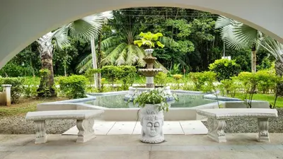 a fountain in the middle of a garden with two benches at Cozy getaway w/pool-tennis-bbq near Manuel Antonio in Manuel Antonio