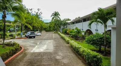 a street with palm trees and cars parked on the road at Cozy getaway w/pool-tennis-bbq near Manuel Antonio in Manuel Antonio