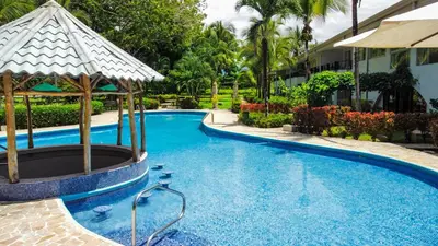 a swimming pool at a resort with an umbrella at Cozy getaway w/pool-tennis-bbq near Manuel Antonio in Manuel Antonio