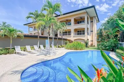 a house with a swimming pool and palm trees at Condo Las Brisas near to Marina Herradura, free Pool and wifi in Herradura