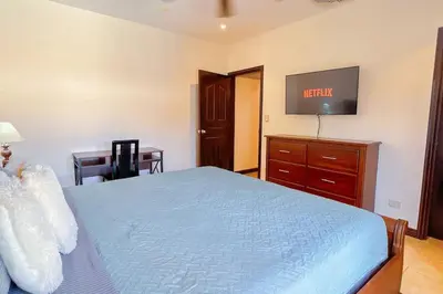 a bedroom with a bed and a desk and a tv at Condo Las Brisas near to Marina Herradura, free Pool and wifi in Herradura