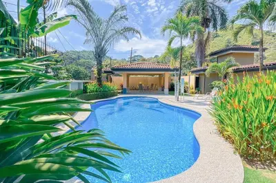 a swimming pool in the backyard of a house with palm trees at Condo Las Brisas near to Marina Herradura, free Pool and wifi in Herradura