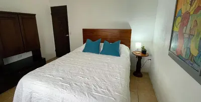 a bedroom with a white bed with blue pillows at Casa Bambu céntrico, lindo y acogedor con A C in General Viejo