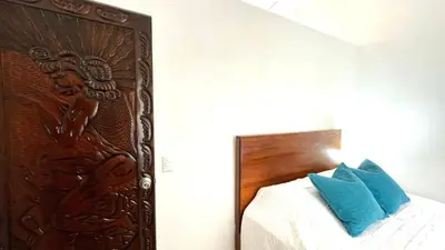 a bedroom with a wooden headboard and a bed with blue pillows at Casa Bambu céntrico, lindo y acogedor con A C in General Viejo