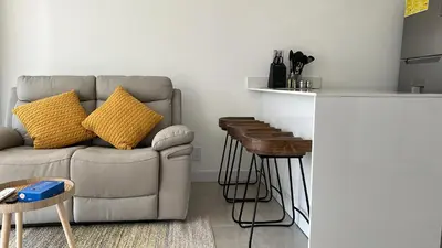 a living room with a couch and two stools at COZY STUDIO near SABANA CENTRAL PARK in San José
