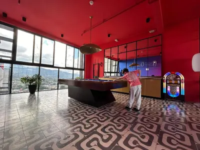 a man standing at a table in a room with red walls at COZY STUDIO near SABANA CENTRAL PARK in San José
