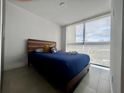 a bedroom with a bed and a large window at COZY STUDIO near SABANA CENTRAL PARK in San José