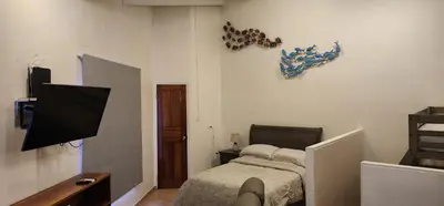 a bedroom with a bed and a tv on a wall at Casa Yorba in Jacó