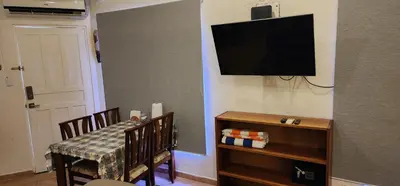 a living room with a television and a table and chairs at Casa Yorba in Jacó