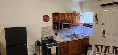 a kitchen with wooden cabinets and a black refrigerator at Casa Yorba in Jacó