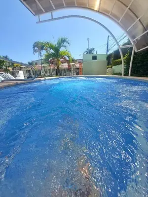 a pool with blue water under a white umbrella at Casa Yorba in Jacó