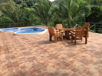 a patio with a table and chairs next to a pool at Pura Natura Lodge Arroyo in Sábalo