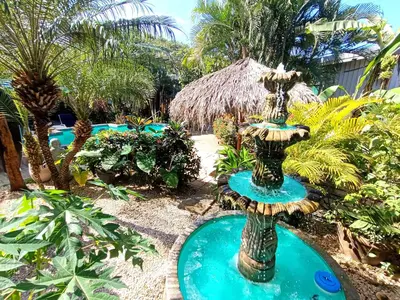 a fountain in the middle of a garden with palm trees at Suite Dream Blue in Tamarindo