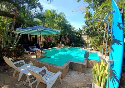 a swimming pool with chairs and an umbrella at Suite Dream Blue in Tamarindo