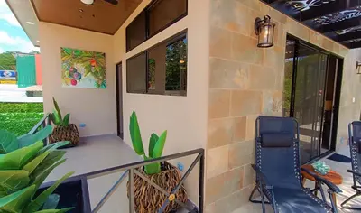 a porch with chairs and a table and some plants at Suite La Orquidea in Tamarindo