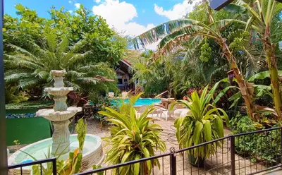 a resort with a pool and a garden with palm trees at Suite La Orquidea in Tamarindo