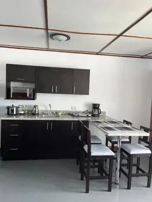 a kitchen with black cabinets and a table with chairs at MARIO in Alajuela City